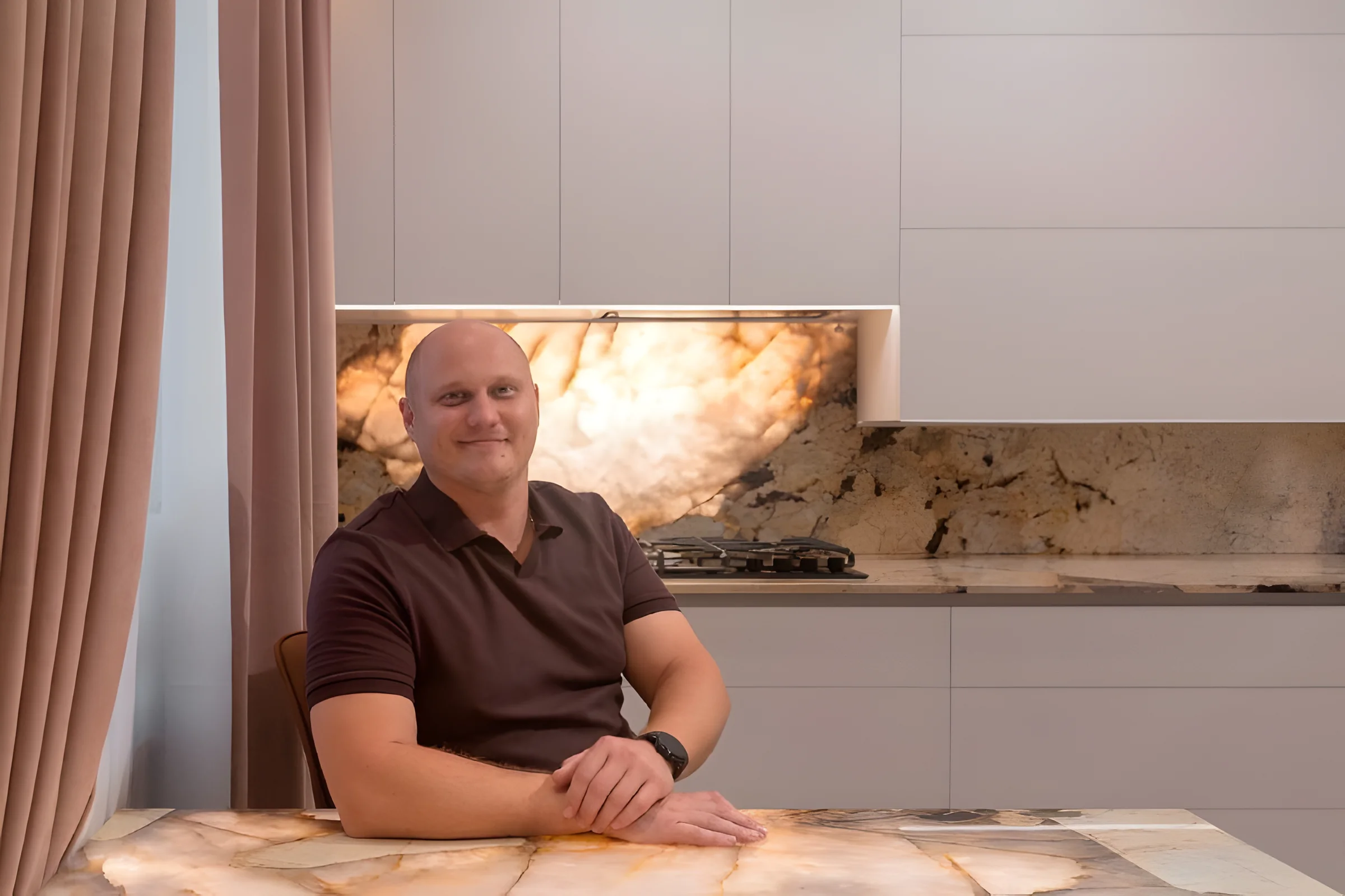 Дмитрий Коротков за столом из подсвеченного натурального камня в кухне проекта 01